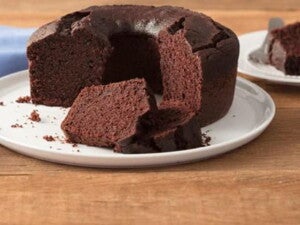Bolo de chocolate com cobertura disposto sobre um prato branco