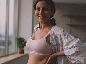 Confident looking woman in a lactation bra, checking her post partum body.