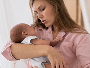Mulher com blusa rosa carregando o recém-nascido no colo Mulher com blusa rosa carregando o recém-nascido no colo