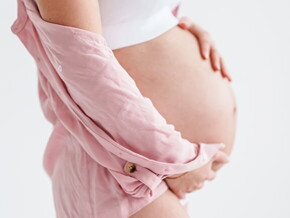 gestante de perfil com as mãos sobre a barriga