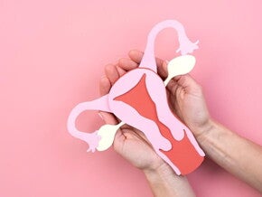 Imagem de mão feminina segurando um desenho de órgão feminino.