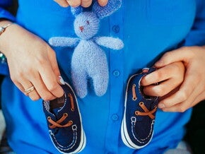 Imagem de um ensaio fotográfico de gestante com a mãe segurando os sapatinhos sobre a barriga Imagem de um ensaio fotográfico de gestante com a mãe segurando os sapatinhos sobre a barriga