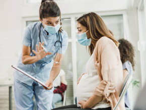 médica dialogando com uma gestante e mostrando uma prancheta