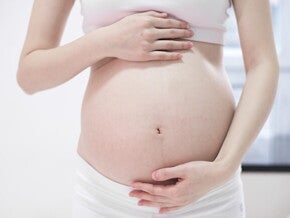 Mulher grávida com as mãos sobre a barriga