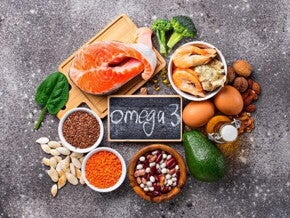 alimentos ricos em ômega 3, como salmão, nozes, sementes e abacate, dispostos sobre uma mesa.
