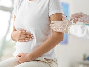 Gestante recebendo vacina no braço durante consulta médica.