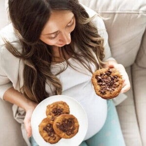 mulher grávida segurando um prato com cookies de chocolate e sorrindo. mulher grávida segurando um prato com cookies de chocolate e sorrindo.