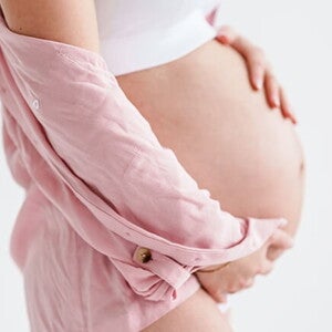 gestante de perfil com as mãos sobre a barriga