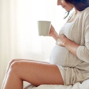 Mulher grávida sentada com uma caneca na mão