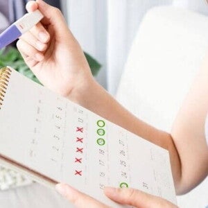 mulher segurando teste de gravidez e calendário com datas marcadas. mulher segurando teste de gravidez e calendário com datas marcadas.