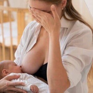 Mulher amamentando bebê recém-nascido com expressão preocupada Mulher amamentando bebê recém-nascido com expressão preocupada