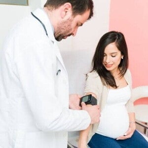Um profissional de saúde realizando um exame em uma gestante sentada.
