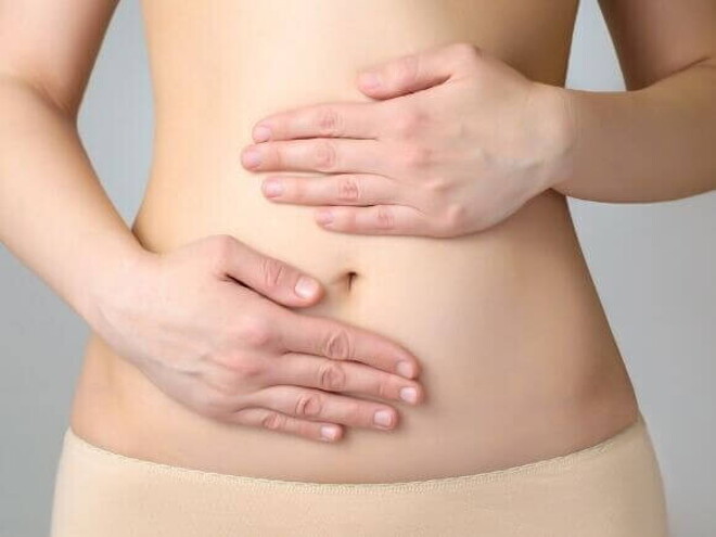 Uma mulher com as mãos sobre a região abdominal Uma mulher com as mãos sobre a região abdominal