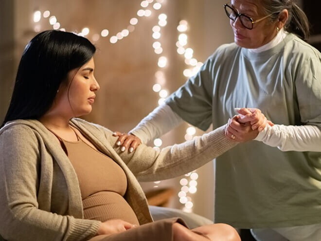 Doula segurando a mão de uma mulher grávida em trabalho de parto, demonstrando apoio e conexão Doula segurando a mão de uma mulher grávida em trabalho de parto, demonstrando apoio e conexão