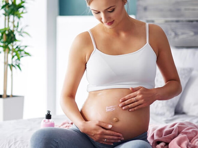 gestante sentada passando creme na barriga gestante sentada passando creme na barriga