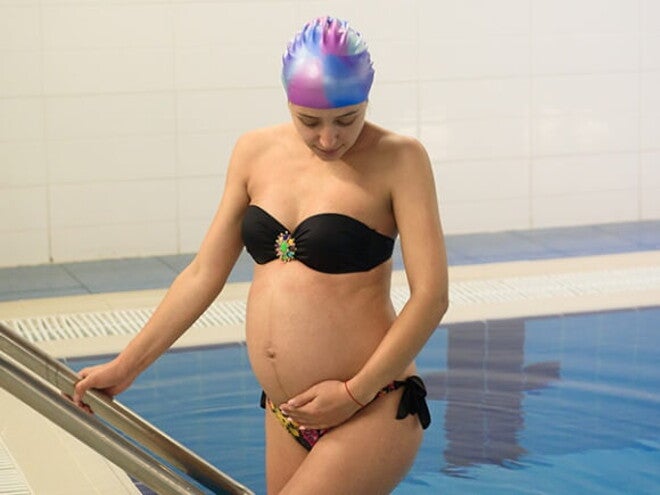 Mulher grávida saindo de uma piscina após aula de hidroterapia Mulher grávida saindo de uma piscina após aula de hidroterapia