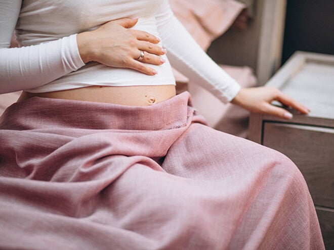 Infecção urinária na gravidez: sintomas, riscos e cuidados mulher grávida sentada na cama com a mãe na barriga