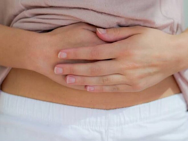 Mulher com cólica menstrual pressionando com força a região abaixo do umbigo. Mulher com cólica menstrual pressionando com força a região abaixo do umbigo.