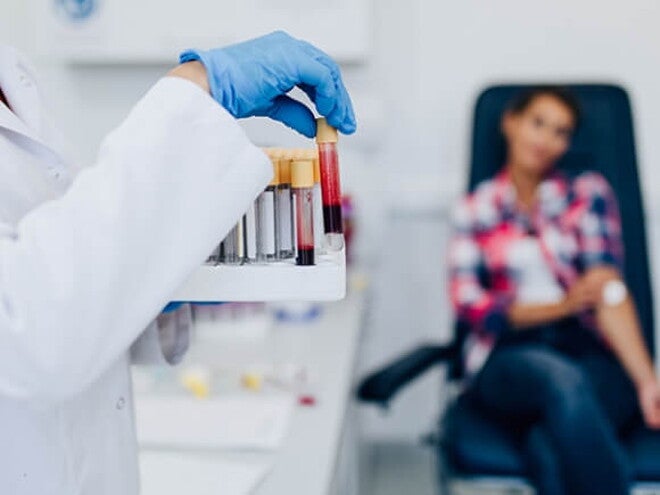 Mulher manuseando tubos de ensaio com amostras de sangue Mulher manuseando tubos de ensaio com amostras de sangue