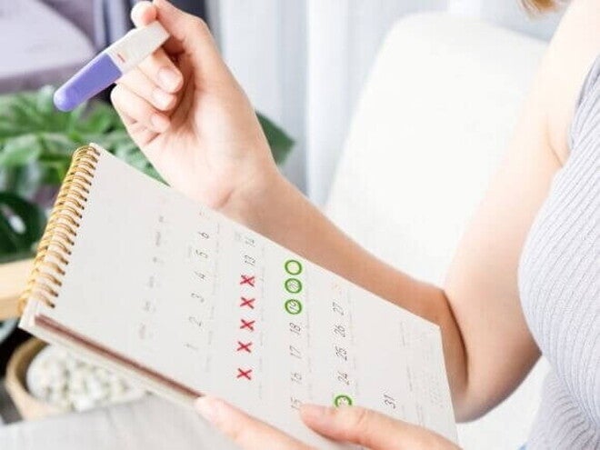 mulher segurando teste de gravidez e calendário com datas marcadas. mulher segurando teste de gravidez e calendário com datas marcadas.