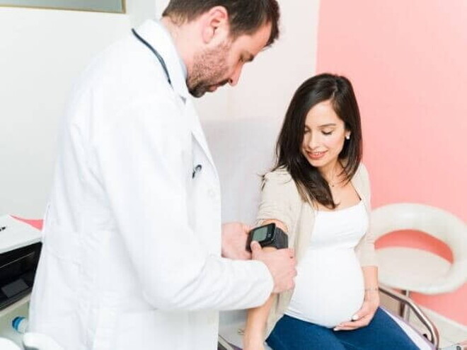 Um profissional de saúde realizando um exame em uma gestante sentada. Um profissional de saúde realizando um exame em uma gestante sentada.