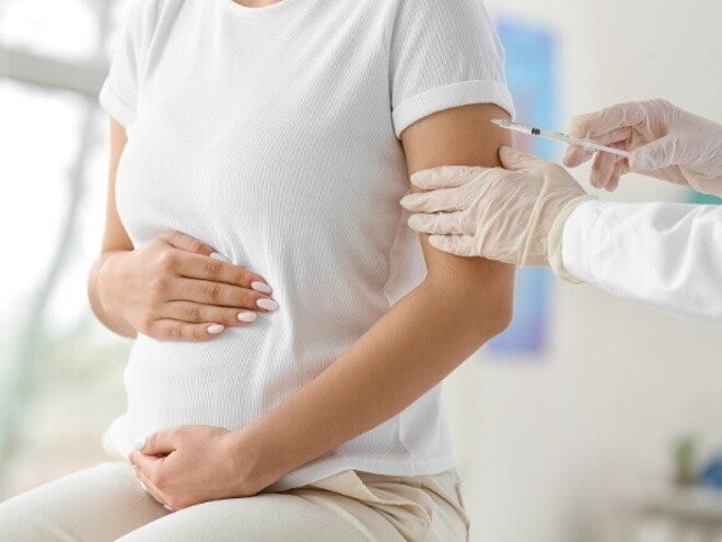 Gestante recebendo vacina no braço durante consulta médica. Gestante recebendo vacina no braço durante consulta médica.