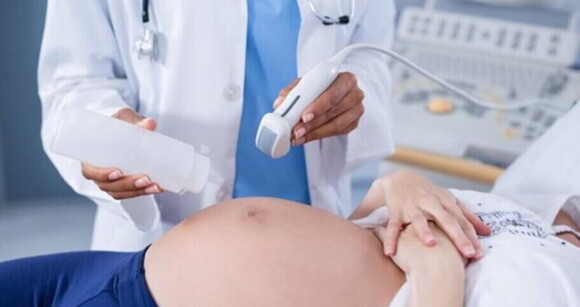 Mulher grávida deitada realizando exame de ultrassonografia Mulher grávida deitada realizando exame de ultrassonografia