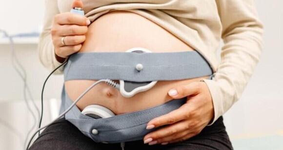 Mulher grávida com cardiotocógrafo preso na região do abdome com faixas elásticas Mulher grávida com cardiotocógrafo preso na região do abdome com faixas elásticas