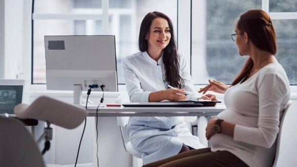médica sorridente conversando com gestante em consultório. médica sorridente conversando com gestante em consultório.