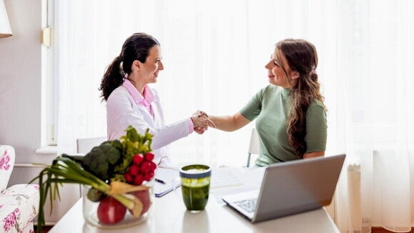 nutricionista cumprimenta gestante em consulta com alimentos saudáveis sobre a mesa. nutricionista cumprimenta gestante em consulta com alimentos saudáveis sobre a mesa.