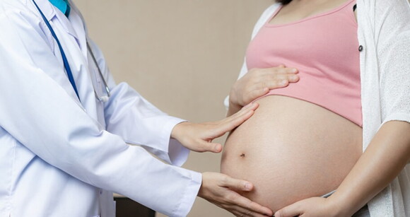 Imagem de um profissional da saúde colocando as mãos em cima da barriga de uma mulher grávida Imagem de um profissional da saúde colocando as mãos em cima da barriga de uma mulher grávida