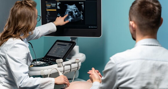 Imagem de uma médica realizando o exame de ultrassonografia em uma gestante Imagem de uma médica realizando o exame de ultrassonografia em uma gestante