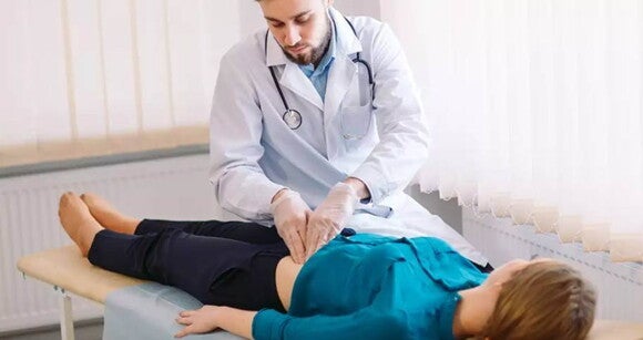 médico examinando o abdômen de uma uma mulher que está deitada em uma maca médico examinando o abdômen de uma uma mulher que está deitada em uma maca