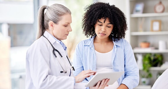 Imagem de uma gestante em um consultório conversando com médica Imagem de uma gestante em um consultório conversando com médica