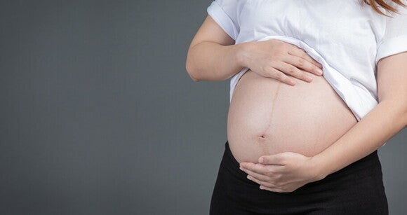 Mulher grávida com as mãos sobre a barriga