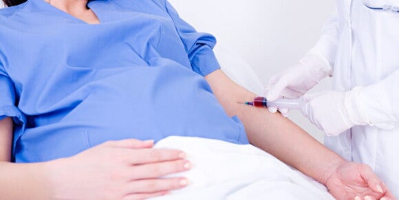 Profissional de saúde coletando sangue do braço de uma mulher grávida que está deitada em uma cama de hospital Profissional de saúde coletando sangue do braço de uma mulher grávida que está deitada em uma cama de hospital