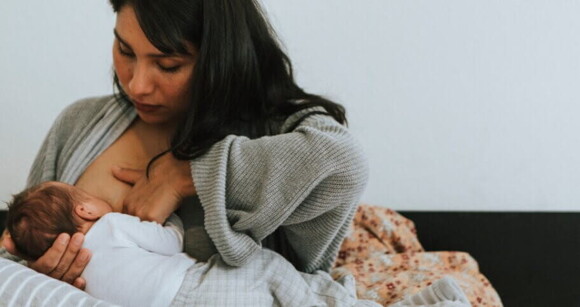 Mulher amamentando bebê recém-nascido na cama Mulher amamentando bebê recém-nascido na cama