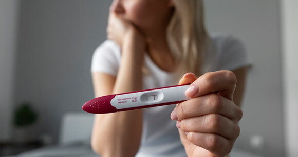 Mulher aflita segurando um teste de grávidez de farmácia com resultado negativo Mulher aflita segurando um teste de grávidez de farmácia com resultado negativo