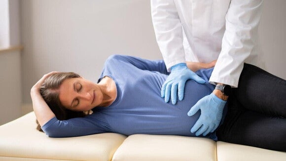 médico realiza versão cefálica externa em gestante deitada de lado. médico realiza versão cefálica externa em gestante deitada de lado.